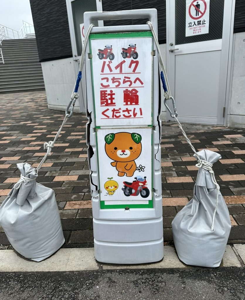 バイクこちらへ駐輪ください　土嚢でがっちり飛ばされん様にみきゃん